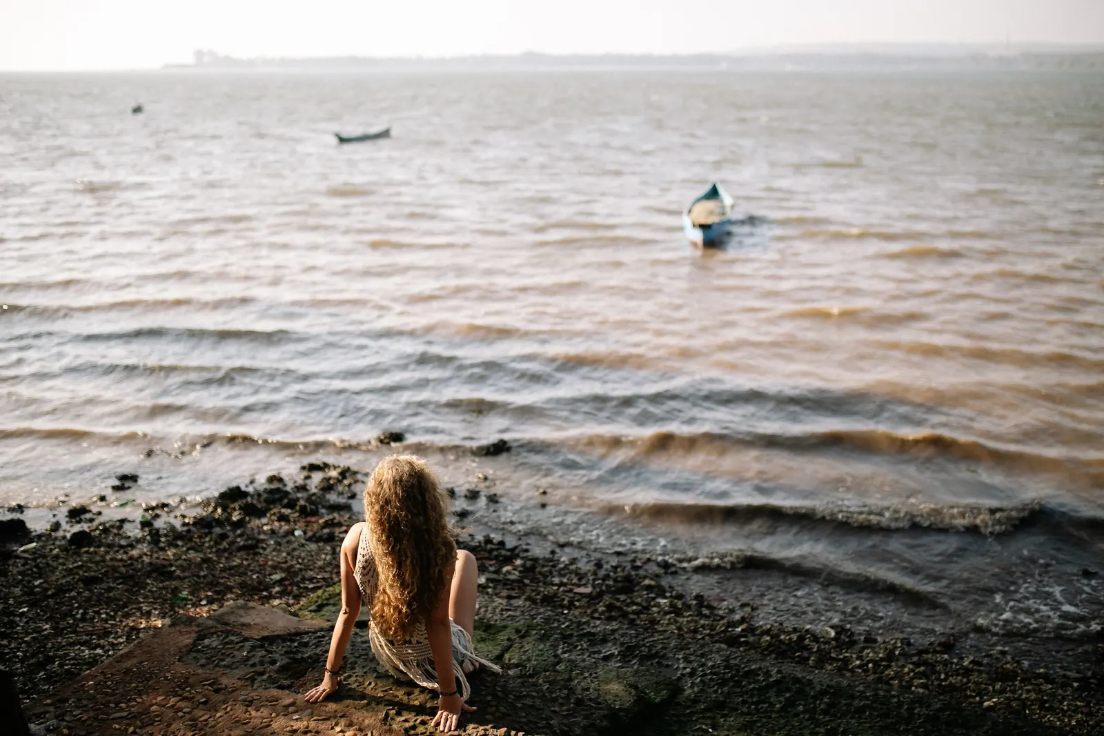 Une femme assise sur le sable face à la mer
